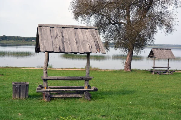 Vecchia panca in legno fatta a mano con tetto vicino al lago per i turisti — Foto Stock
