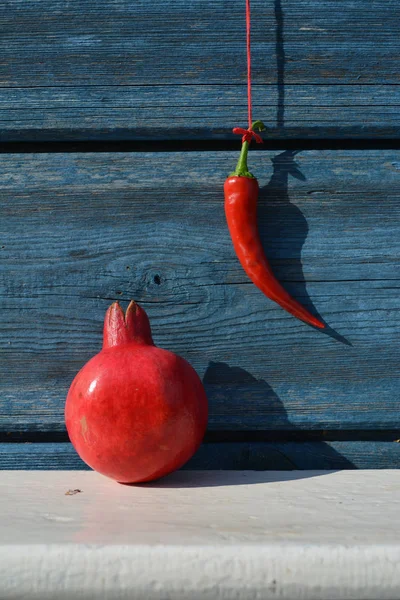 Κόκκινη πιπεριά τσίλι κρεμασμένη σε ξύλινο τοίχο και ρόδι στο ράφι — Φωτογραφία Αρχείου