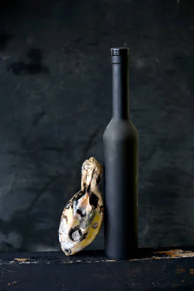 Натюрморт с черной бутылкой вина и гнилыми цуккини — стоковое фото