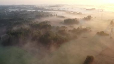 Güneş doğduktan sonra bahçeleri, tarlaları ve elektrik hatlarıyla sihirli sisli sabah manzarası, hava manzarası