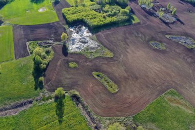 Doğa parkında yeni sürülmüş ıslak ilkbahar tarlası, hava manzarası.