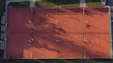 Tenis oyuncuları grubu akşam sahasında oynuyor, hava görüşü