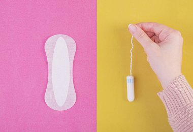 Hijyen bakımı sırasında kritik gün. Bir tampon ve sıhhi bir yastık arasında seçim yapma. Adet döngüsü. Kadın tampon elinde tutar. Üstten Görünüm