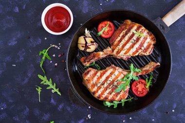 Koyu arka plan üzerinde otlar ile çiğ domuz biftek. Kemik üzerinde ham sulu biftek. Üstten Görünüm