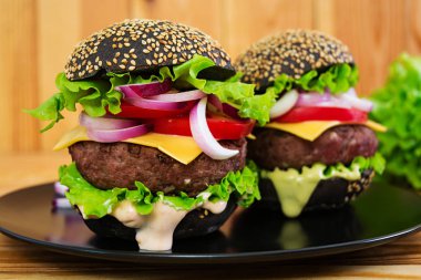 Ahşap arka plan olarak el yapımı burger. Lezzetli siyah burger