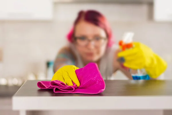 Woman in protective gloves wiping dust using cleaning spray and duster. Cleaning service concept.