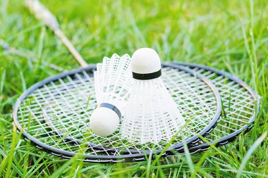 Shuttlecock ve badminton raketleri yeşil bir çim üzerinde