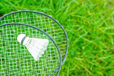 Shuttlecock ve badminton raketleri yeşil bir çim üzerinde
