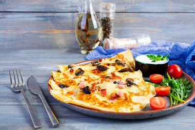 Mantarlı leziz krepler, jambon ve peynir, roka, domates ve ahşap zemin üzerinde ekşi krema.