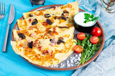 Mantarlı leziz krepler, jambon ve peynir, roka, domates ve ahşap zemin üzerinde ekşi krema.