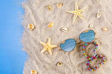 Yaz dönemi. Deniz kabuklu deniz kumu, deniz yıldızı ve güneş gözlüğü. Yaz tatili kavramı