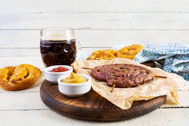 Ekim Festivali için yemek menüsü. Farklı soslu sosis, simit ve bir bardak koyu bira.