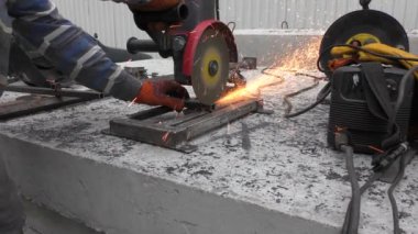 İşçi bir açı öğütücüyle metali keser.
