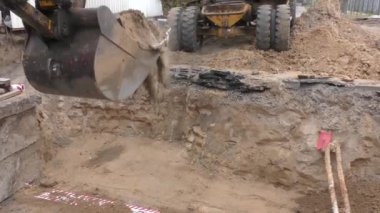 Tekerlek kazıcısı çalışıyor. Bir kova ile donatılmış..