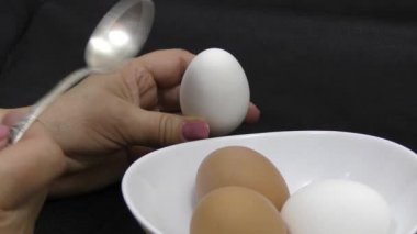 Kaynamış yumurtayı çay kaşığıyla çırp. Koyu arkaplan.