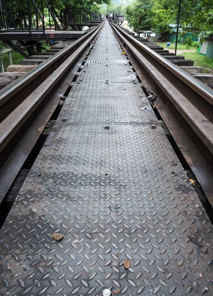 Closeup of the metal pathway on the old railway bridge with the blur trourist background, Kanchanaburi Thailand.