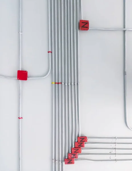 Electrical conduit system attached on the office ceiling with the red control box.
