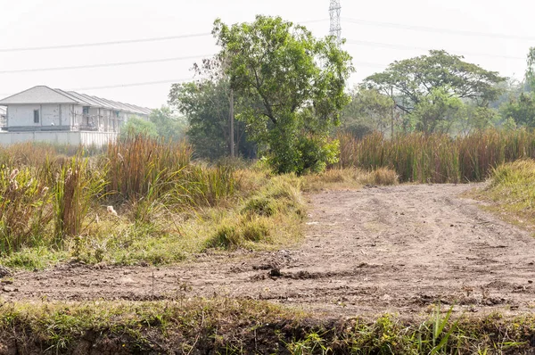 Estrada de terra através do campo de grama para o local de construção . — Fotografia de Stock