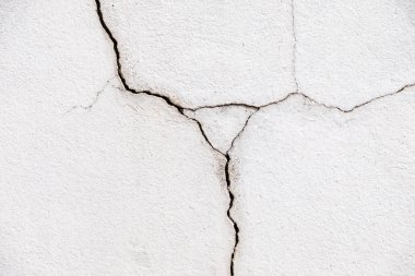 Beyaz beton duvarda uzun çatlak.