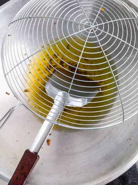 Large colander on the metal pan with the cooking oil. — Stock Photo, Image
