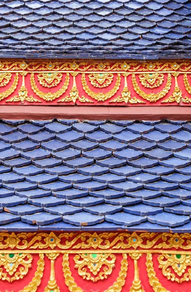 Blue tile with the golden flower sculpture in the traditional Thai style on the church roof in Thai temple.