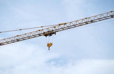 Mavi gökyüzünün altındaki kule vincinin uzun vadisindeki motor makarasıyla büyük bir kanca. Şehirdeki kentsel gelişim projesi..