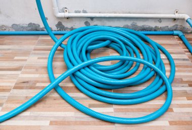 Lastik sulama hortumu şehir evinin terasının yanındaki fayans zemininde yatıyor..