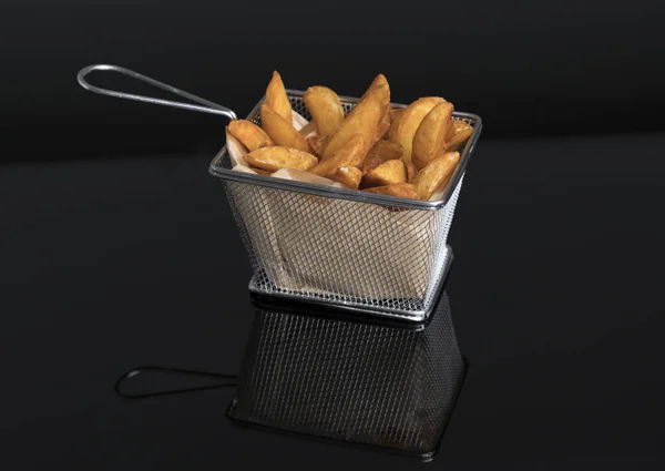Жареные картофельные клинья на черном метакрилате в металлической корзине VI — стоковое фото