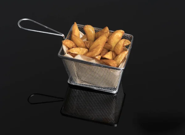 Stekt potatis kilar på svart metakrylat i metall korg — Stockfoto
