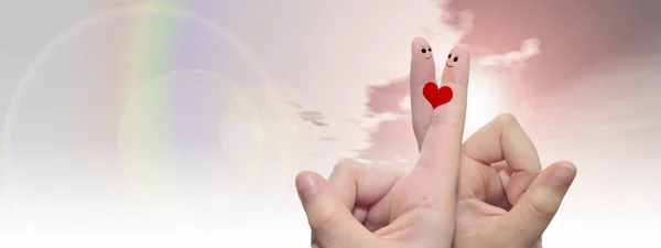 Concept or conceptual human or female hands with two fingers painted with a red heart and smiley faces over rainbow sky background banner