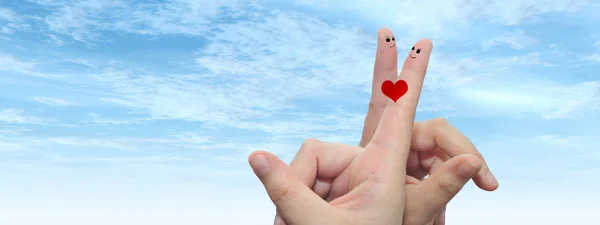 Concept or conceptual human or female hands with two fingers painted with a red heart and smiley faces over cloud blue sky background banner