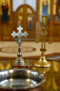 Ortodoks kilisesinin iç kısmı, burada şamdanın haç şeklindeki detayları ve vaftiz töreninde kullanılan metal haç üzerinde duruluyor.