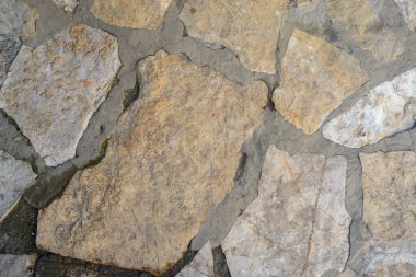 Doğal bir taşın dokusu, çok geniş eklemleri ve su ile döşenmiş, eklemlerin bir kısmını ve taşın bir kısmını koyulaştırmış.