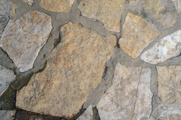 Doğal bir taşın dokusu, çok geniş eklemleri ve su ile döşenmiş, eklemlerin bir kısmını ve taşın bir kısmını koyulaştırmış.