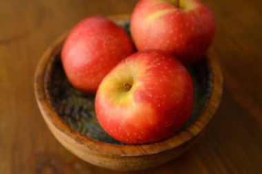 Three delicious and healthy red ripe apples in a wooden bowl