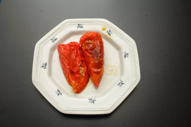 Doldurulmuş kırmızı dolma biber, içi et dolu, beyaz bir tabakta yemeye hazır.