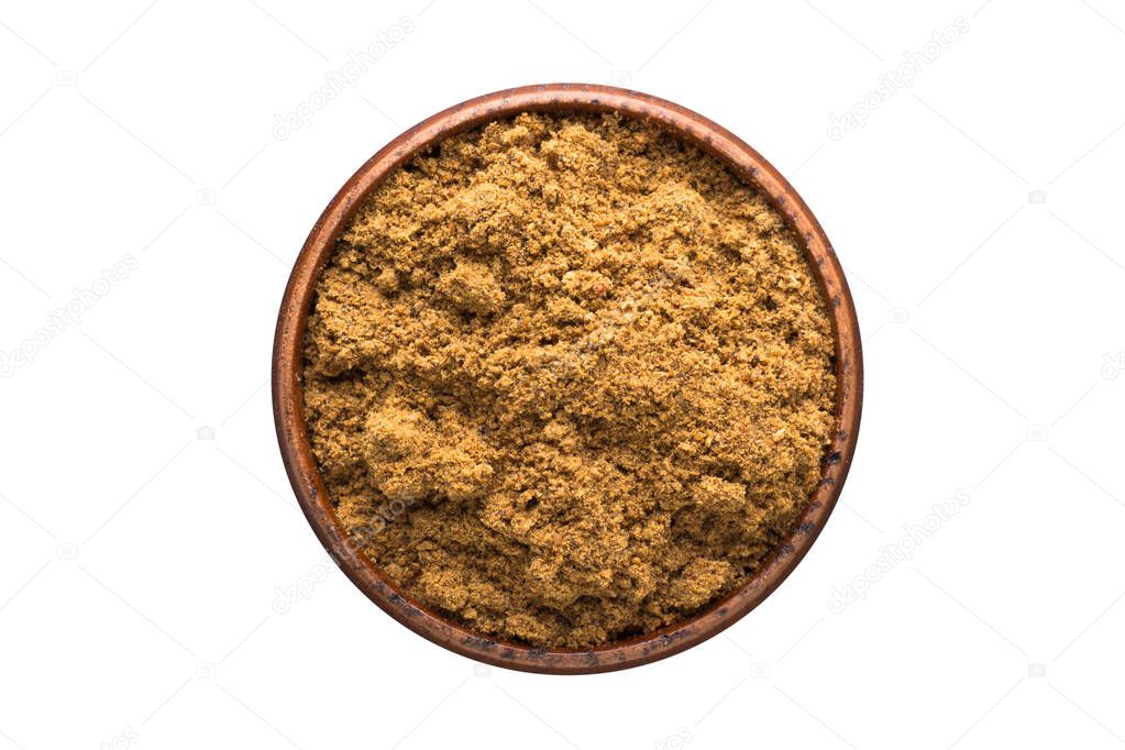 ground nutmeg powder seasoning in a wooden bowl, top view. spice isolated on white