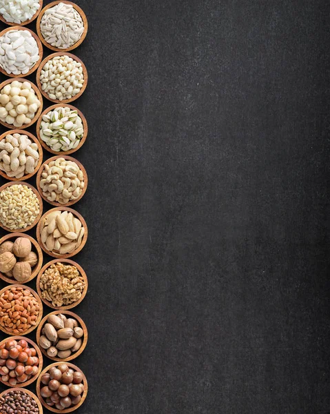 Assorted nuts and seeds on black table with copy space, organic — Stock Photo, Image