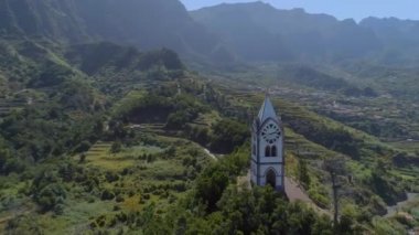 Eski kilise ve dağlık bir manzara içinde bir tepede Saat Kulesi