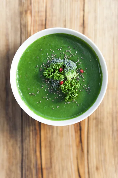 Spinach green soup with broccoli in white bowl on wooden background top view. — Stock Photo, Image