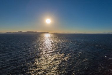 Egina adası arka plan ile deniz üzerinde batan güneşin Yansımaları