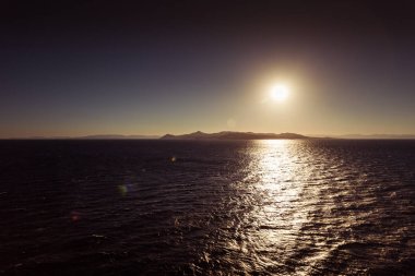 Egina adası arka plan ile deniz üzerinde batan güneşin Yansımaları