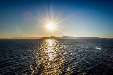 Saronic Körfezi arka plan adaları ile gün batımında deniz üzerinde Yansımalar