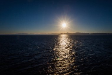 Saronic Körfezi arka plan adaları ile gün batımında Yansımalar