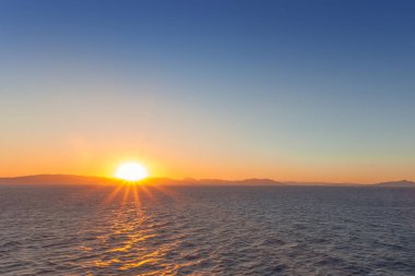 Saronik Körfezi adalarının profilinin arkasına batmak üzere olan Güneş