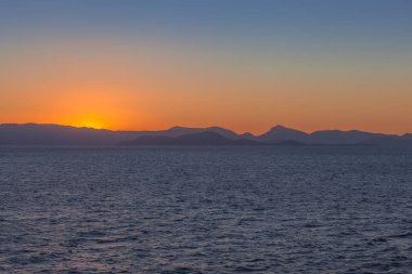Saronic Gulf adaları profilinin arkasında batan güneş