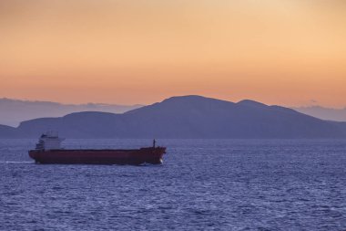 Ada siluet arka plan ile gün batımında gemi yelken