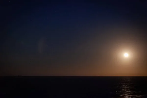 Luna iluminando el cielo sobre el mar — Foto de Stock