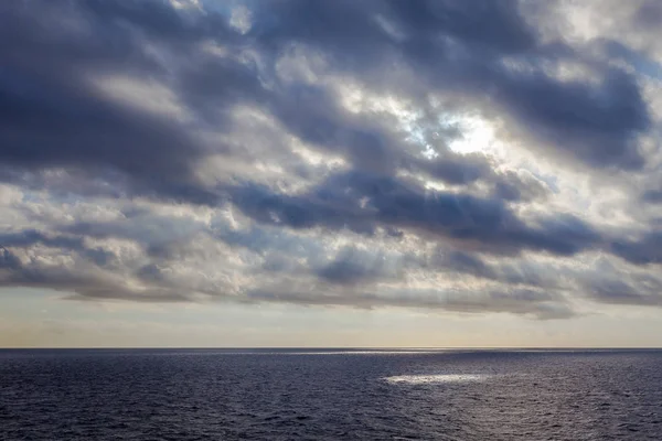 Rayos del sol filtrándose a través de las nubes sobre el mar — Foto de Stock