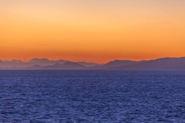 Ufukta turuncu gökyüzü ve Ege Denizi adaları ile muhteşem gün batımı